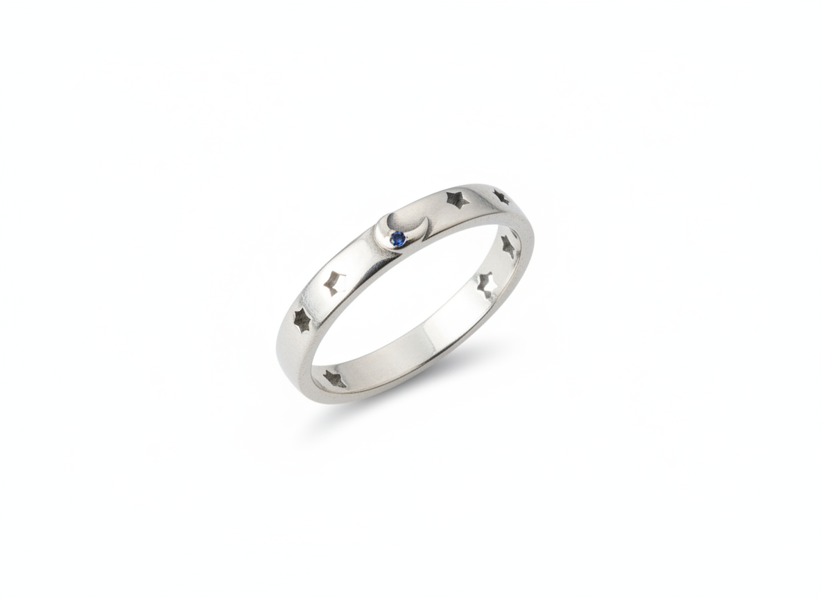 A silver band ring featuring a small crescent moon and star motif, accented with a tiny blue gemstone, shown on a plain white background.